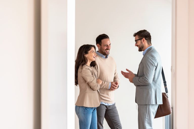 Young married couple talking with a real-estate agent visiting a